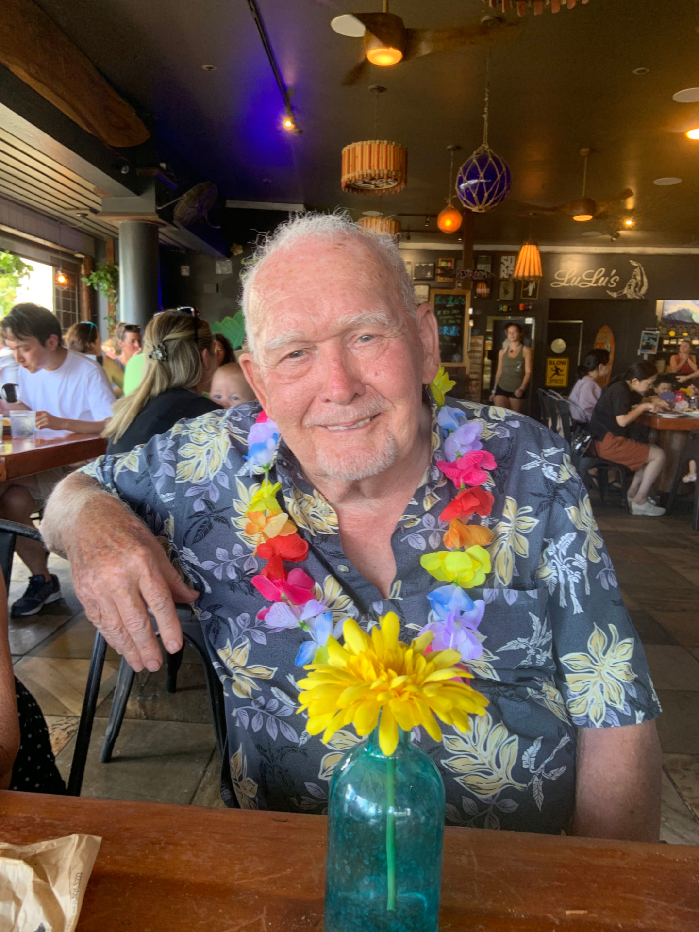 Herb Brokop smiling in a Hawaiian shirt and a flower lei at a restaurant in Hawaii